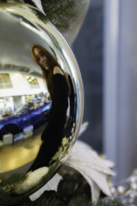 Reflective chrome Christmas ornament showing showroom and blue car reflection