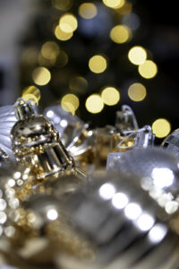 Silver bell-shaped Christmas ornaments with golden bokeh lights in background