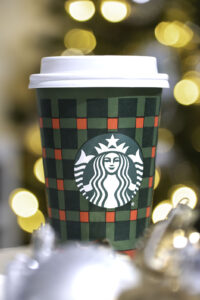 Green plaid Starbucks holiday cup with golden bokeh lights and ornaments